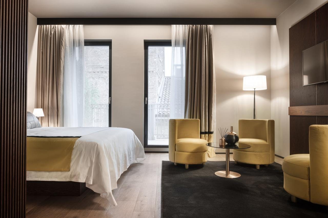 Camera d’hotel con poltroncine gialle e tende in seta