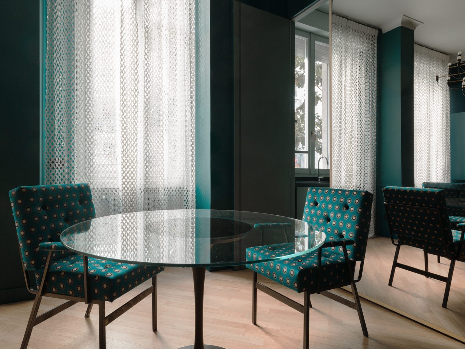 Sala da pranzo verde petrolio con tende traforate